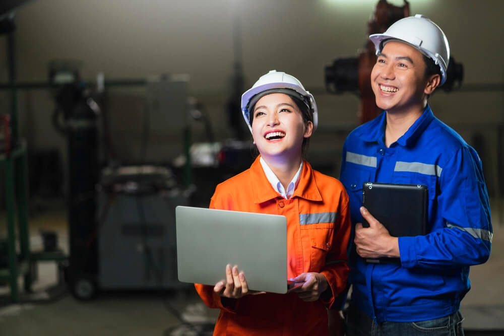 portrait asian emgineer male female technician safty uniform standing turn around look camera laugh smile with cheerful confident machinery factory workplace background 2 1